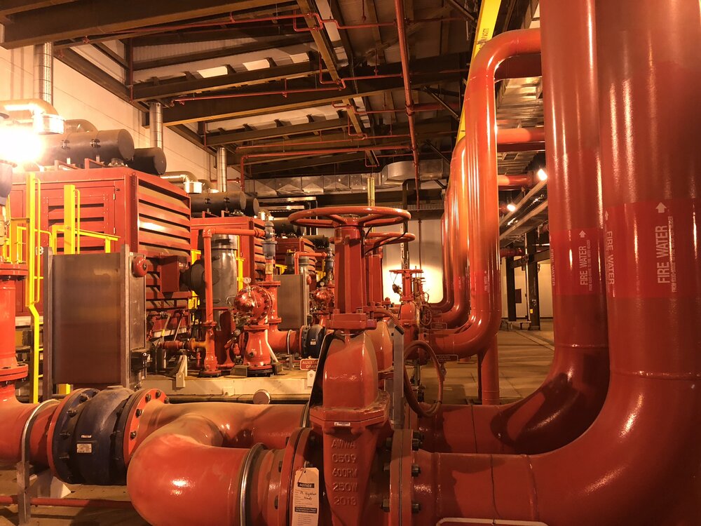 Fire water pump house with red firewater piping and pumps at Suncor