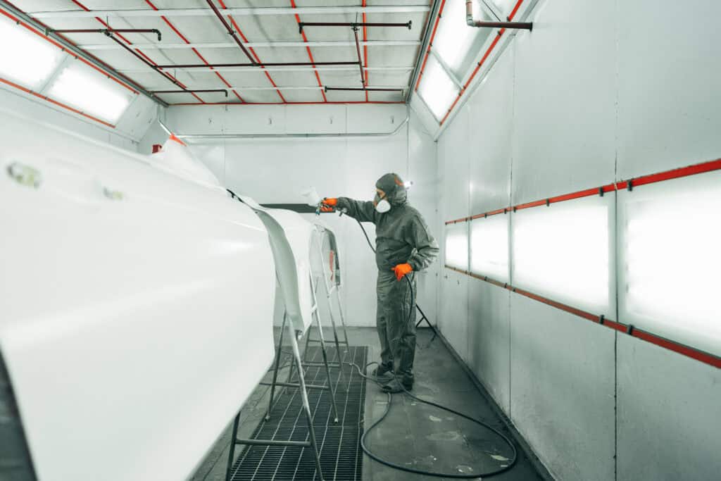 Auto painter spray painting inside a paint booth