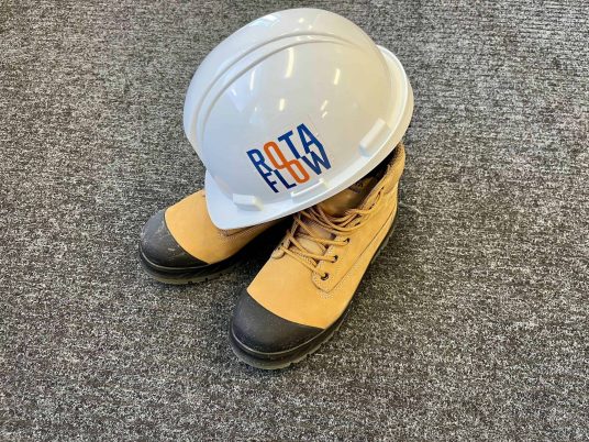 Rotaflow branded hard hat resting on safety work boots